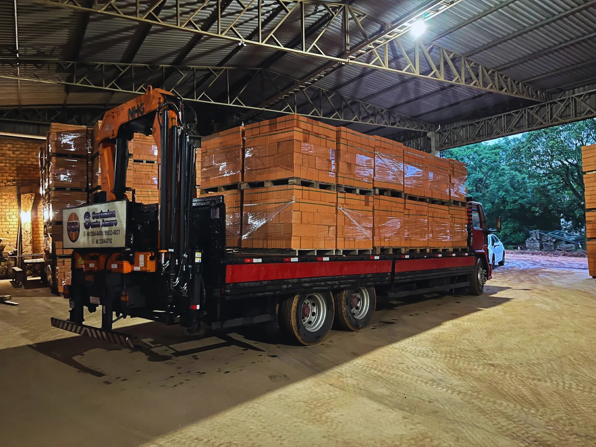 Caminhão munck carregado de paletes, saindo da fábrica